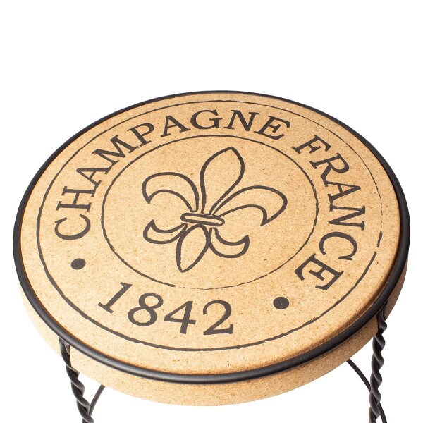 Overhead view of a table with a cork top and metal base. "Champagne France, 1842" printed on the cork top.